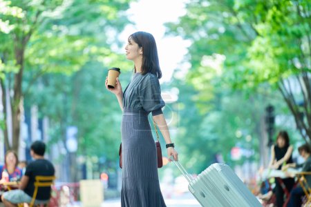 Foto de Una mujer caminando por la ciudad con una maleta en un buen día - Imagen libre de derechos