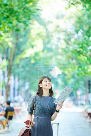 Téléchargez les photos : Une femme tenant une carte et un smartphone dans la rue - en image libre de droit