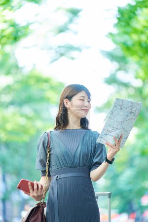 Foto de Una mujer sosteniendo un mapa y un smartphone en la calle - Imagen libre de derechos