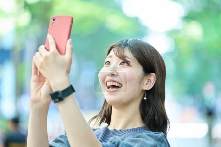 Foto de Mujer joven sosteniendo un teléfono inteligente al aire libre - Imagen libre de derechos