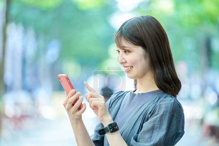 Foto de Mujer joven mirando la pantalla del teléfono inteligente en buen día - Imagen libre de derechos