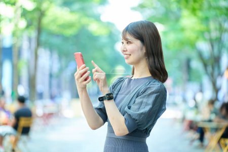 Photo for Young woman looking at smartphone screen on fine day - Royalty Free Image