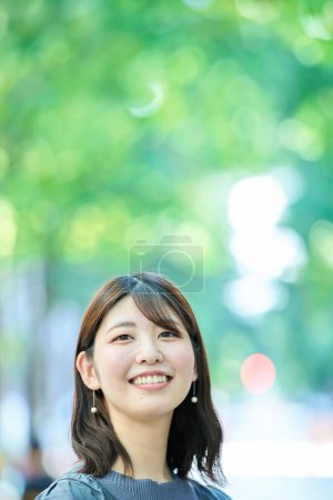 Téléchargez les photos : Portrait de femme souriante dans la rue verte le beau jour - en image libre de droit