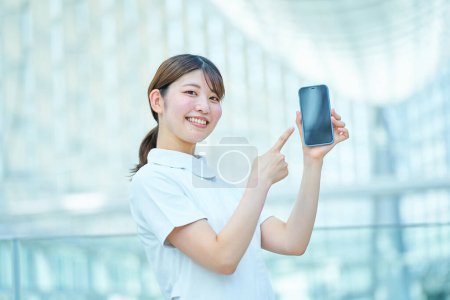 Photo for A woman in a white coat holding a digital device indoors - Royalty Free Image