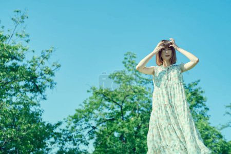 Téléchargez les photos : Jeune femme marchant dans un espace vert avec une expression détendue - en image libre de droit