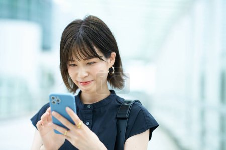 Téléchargez les photos : Jeune femme opérant un smartphone à l'extérieur - en image libre de droit