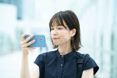 Téléchargez les photos : Jeune femme regardant l'écran du smartphone en plein air - en image libre de droit