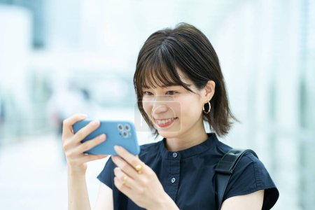 Foto de Mujer joven mirando la pantalla del teléfono inteligente al aire libre - Imagen libre de derechos