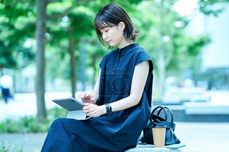Foto de Mujer joven operando una tableta PC al aire libre - Imagen libre de derechos