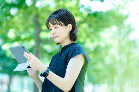 Téléchargez les photos : Jeune femme opérant une tablette PC à l'extérieur - en image libre de droit