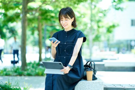 Foto de Mujer joven operando una tableta PC al aire libre - Imagen libre de derechos