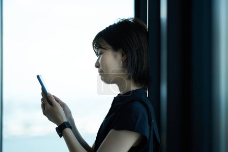 Photo for Asian young woman holding a smartphone - Royalty Free Image