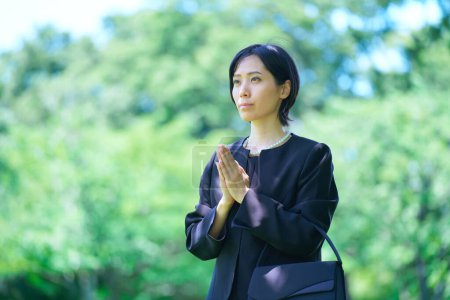 Photo for A woman who puts her hands together in a mourning dress outdoors - Royalty Free Image