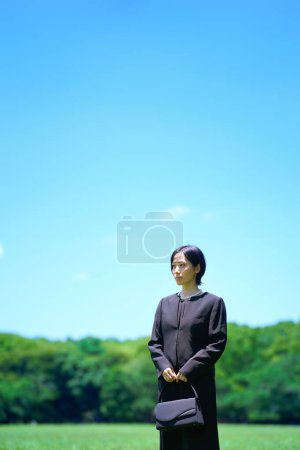 Téléchargez les photos : Une femme en deuil debout dans un espace vert - en image libre de droit
