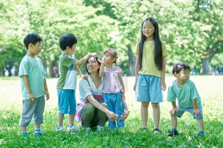 Photo for Children and woman in a apron lined up in a green space - Royalty Free Image