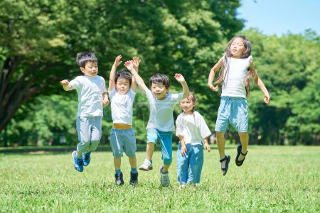 Téléchargez les photos : Les enfants sautent ensemble dans le parc le beau jour - en image libre de droit