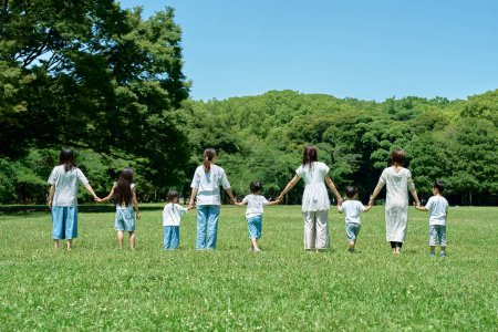 Téléchargez les photos : Vue arrière des parents et des enfants alignés dans un champ - en image libre de droit