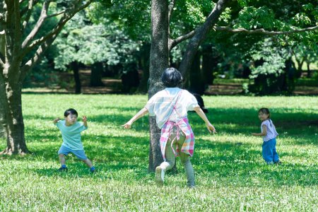 Téléchargez les photos : Une femme dans un tablier avec des enfants jouant à la chasse dans le parc - en image libre de droit