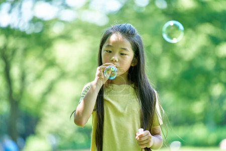 Foto de Chica jugando con burbujas de jabón en el parque - Imagen libre de derechos