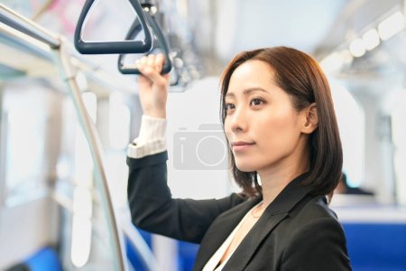 Photo for A business woman stands holding a train strap - Royalty Free Image