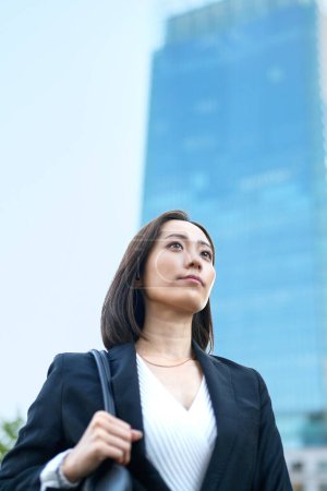 Photo for Business woman looking up at the sky in the town - Royalty Free Image