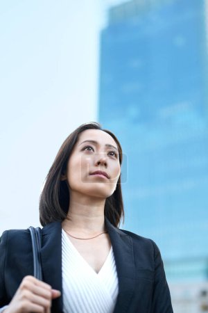 Téléchargez les photos : Femme d'affaires regardant le ciel dans la ville - en image libre de droit