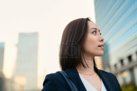 Téléchargez les photos : Femme d'affaires regardant le ciel dans la ville - en image libre de droit