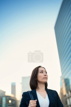 Photo for Business woman looking up at the sky in the town - Royalty Free Image