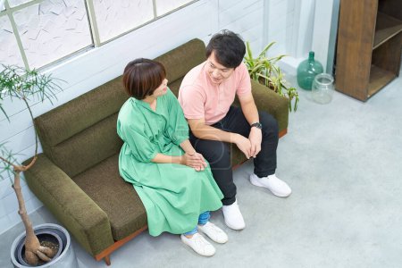 Photo for Young man and woman sitting on the sofa and talking - Royalty Free Image