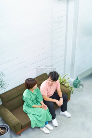 Foto de Hombre y mujer jóvenes sentados en el sofá y hablando - Imagen libre de derechos