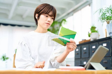 Téléchargez les photos : Jeune femme regardant son livre de banque à l'intérieur - en image libre de droit