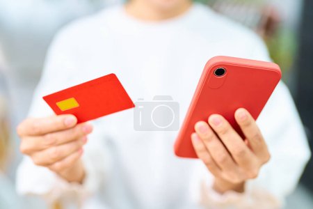 Foto de Mano de una mujer sosteniendo una tarjeta de crédito y un teléfono inteligente en el interior - Imagen libre de derechos