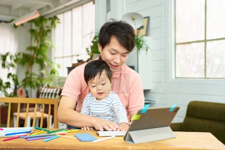 Téléchargez les photos : Un homme tenant un bébé et utilisant un ordinateur - en image libre de droit