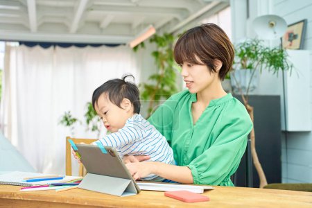 Téléchargez les photos : Une femme qui travaille à la maison avec un bébé - en image libre de droit