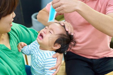 Téléchargez les photos : Parents réconfortant un bébé qui pleure et qui est malade - en image libre de droit