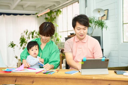 Téléchargez les photos : Une femme tenant un bébé et un homme utilisant un ordinateur - en image libre de droit