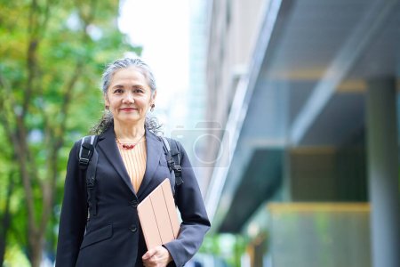 Téléchargez les photos : Sourire femme d'affaires aux cheveux gris sortir - en image libre de droit