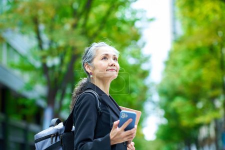 Téléchargez les photos : Femme âgée tenant un smartphone à l'extérieur - en image libre de droit