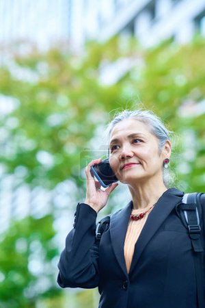 Photo for Senior woman talking on smartphone outdoors - Royalty Free Image