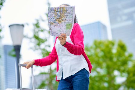 Photo for Senior woman walking outdoors with a map in hand - Royalty Free Image