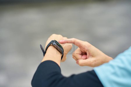 Téléchargez les photos : Main d'une femme âgée opérant une smartwatch en plein air - en image libre de droit