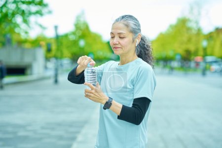 Foto de Mujer mayor bebiendo agua de una botella de plástico al aire libre - Imagen libre de derechos