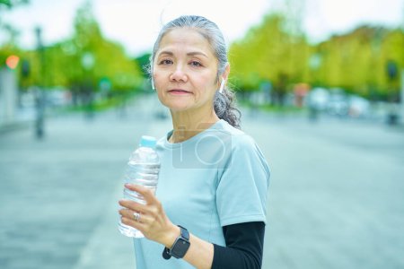Photo for Senior woman drinking water from a plastic bottle outdoors - Royalty Free Image