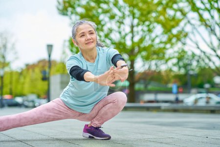 Téléchargez les photos : Femme âgée souriante faisant de l'exercice à l'extérieur - en image libre de droit