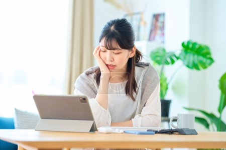 Téléchargez les photos : Une jeune femme à l'air fatiguée en travaillant sur un ordinateur dans sa chambre - en image libre de droit