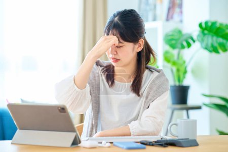 Foto de Una mujer se siente estresada mientras opera una computadora en su habitación - Imagen libre de derechos