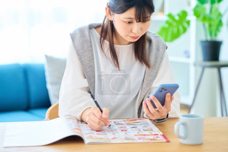 Photo for Young woman checking an advertising booklet in the room - Royalty Free Image