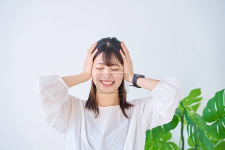 Photo for Young woman holding her head indoors - Royalty Free Image
