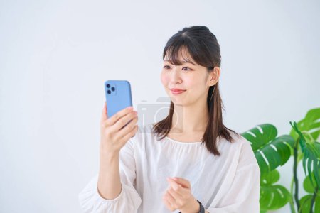 Foto de Mujer joven mirando la pantalla del teléfono inteligente en el interior - Imagen libre de derechos