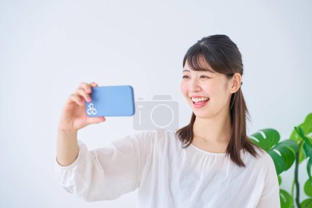Téléchargez les photos : Jeune femme regardant l'écran du smartphone à l'intérieur - en image libre de droit